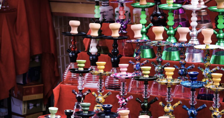A variety of hookahs of all colors on a table.